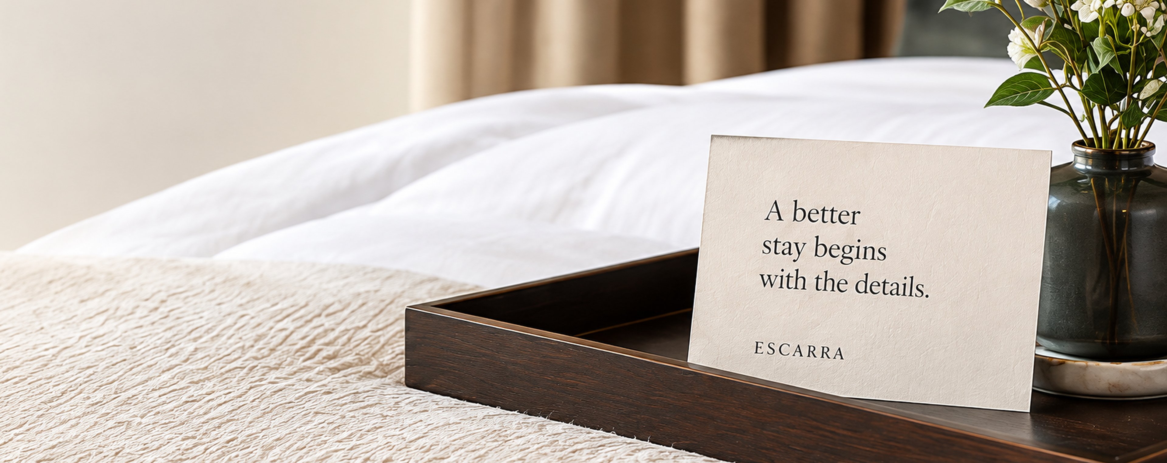 Hotel bed with an Escarra welcome card on a tray